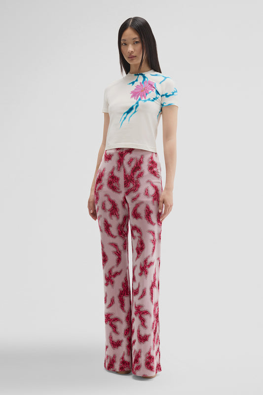 Woman wearing a white t-shirt with floral design and red patterned pants on a white background